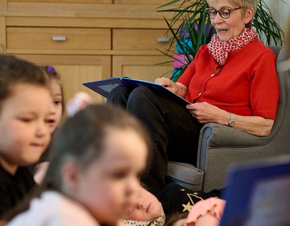 Eine Frau liest Kindern ein Buch vor.
